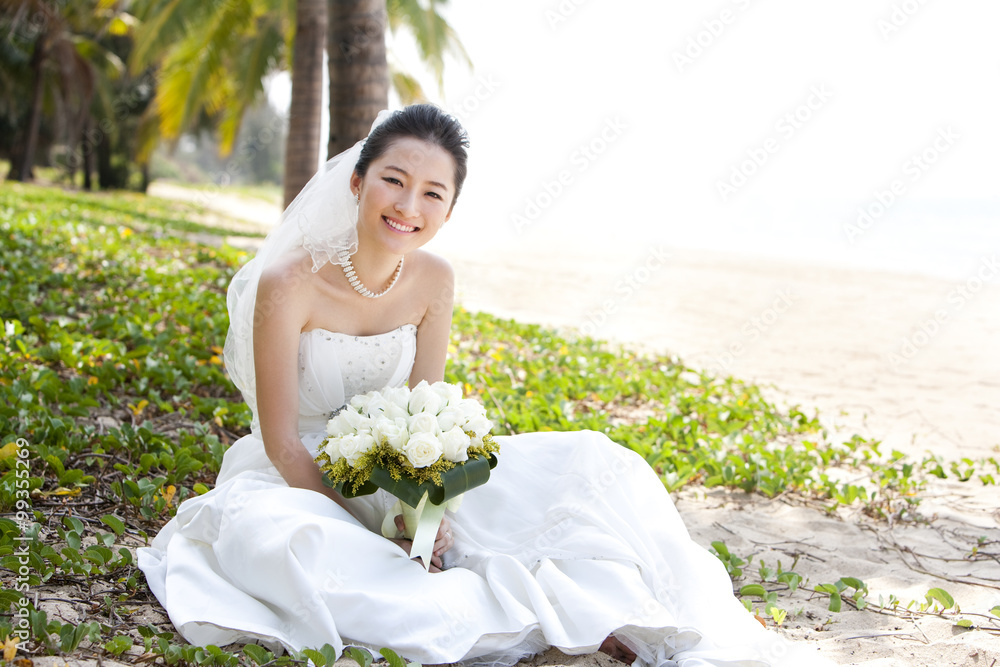 Happy bride sitting on the beach