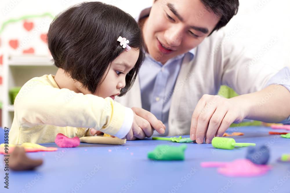 幼儿园老师和可爱的女孩和孩子们玩粘土