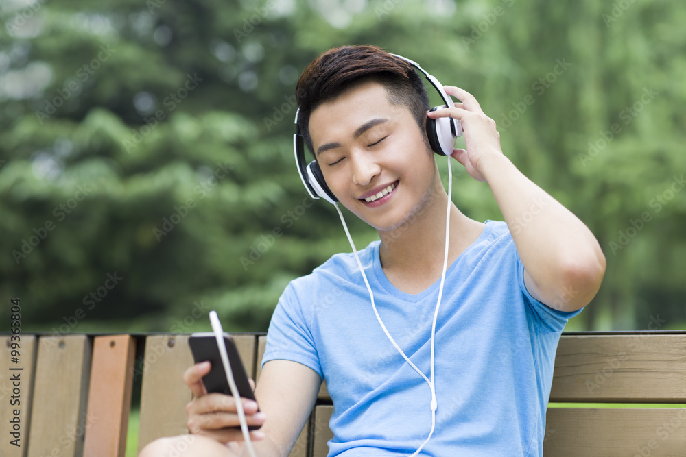 Young man enjoying music in park