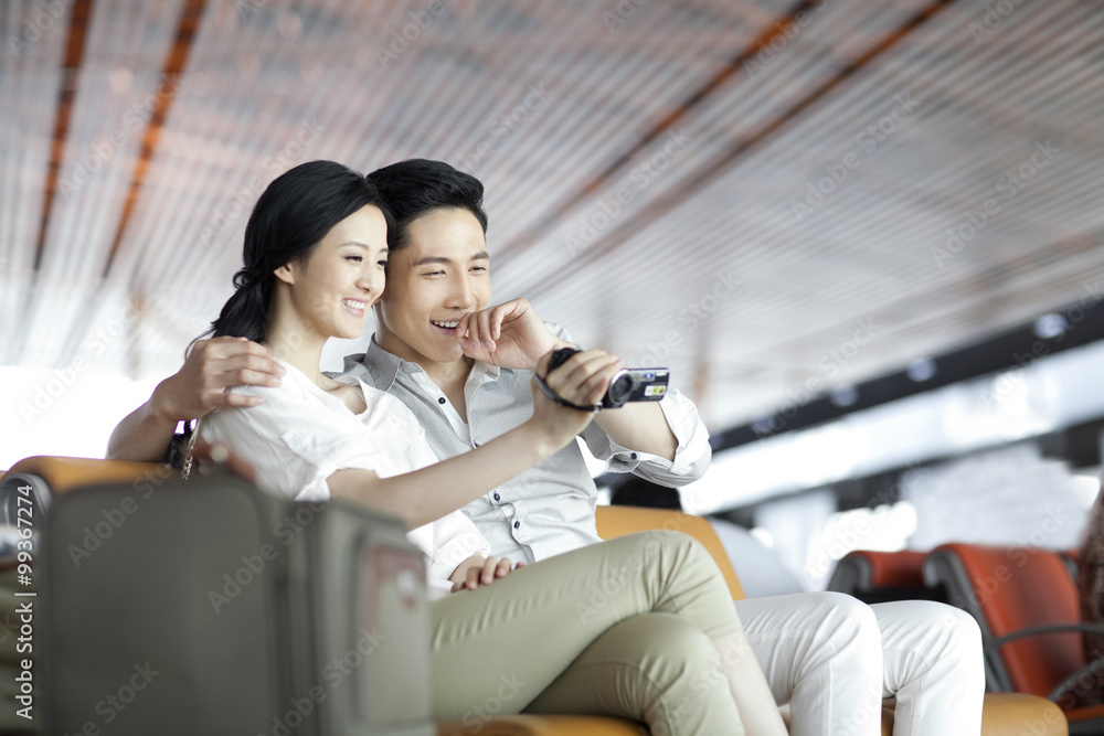 Young couple with camera in airport lounge