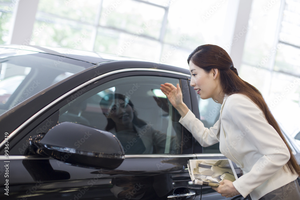 Young businesswoman choosing car in showroom