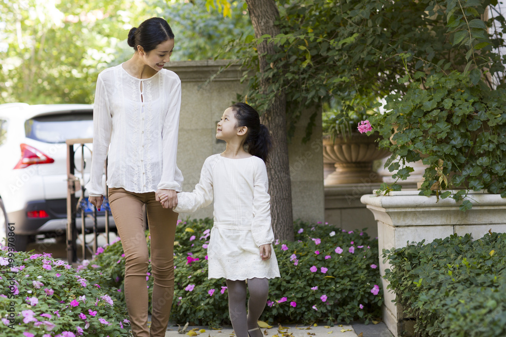 Mother and daughter holding hands walking together