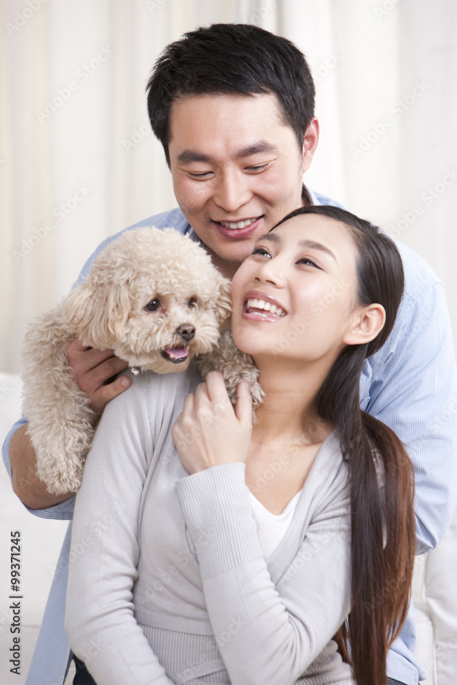 Young couple playing with a pet toy poodle