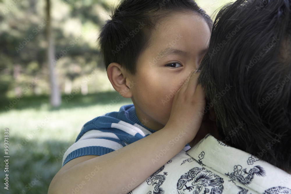 Young Boy Whispering Secrets To An Adult