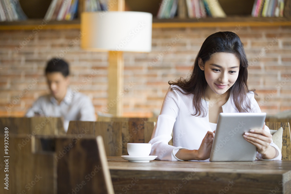 Young woman using digital tablet in cafe