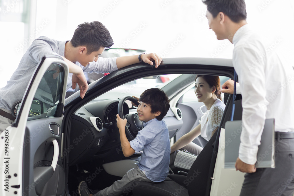 Young family choosing car in showroom