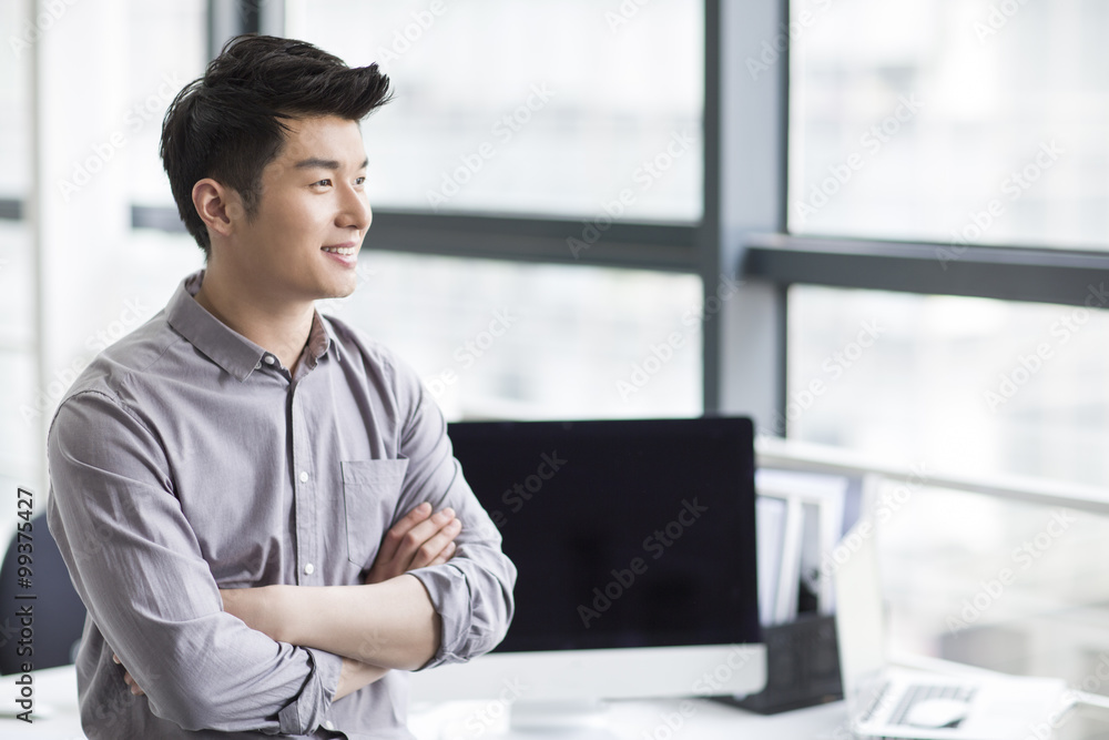 Young businessman looking through window in office