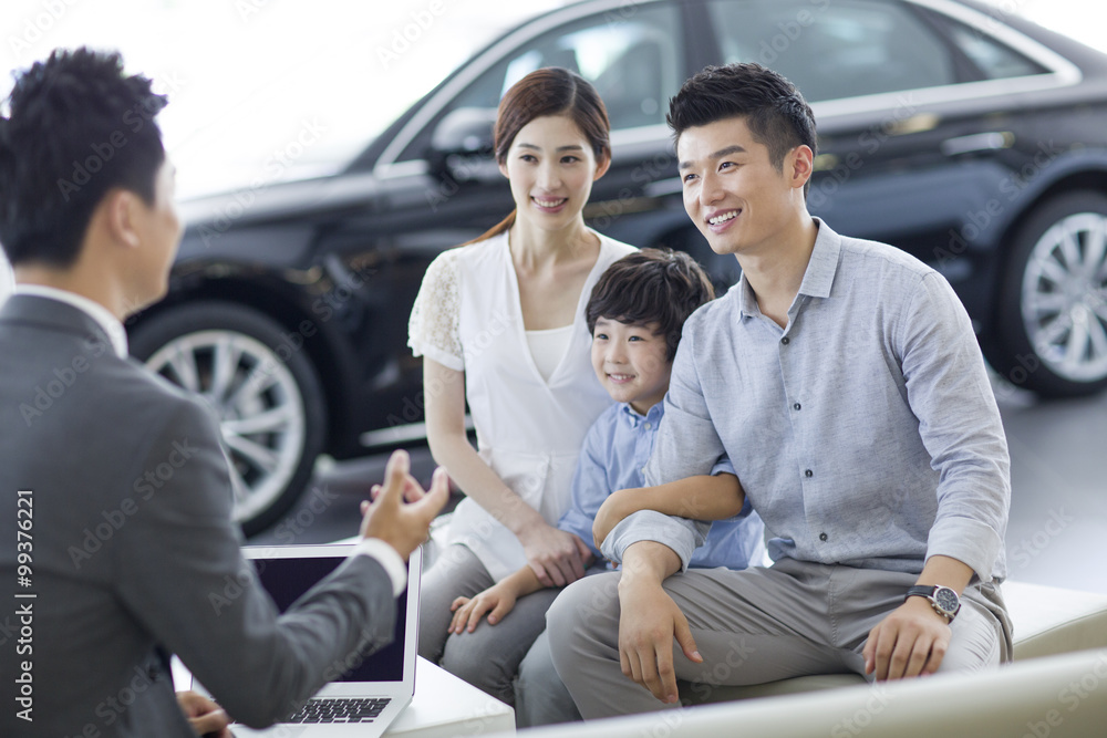 Young family buying car in showroom