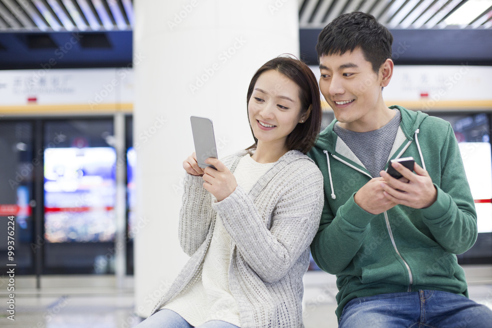 Young couple using smart phone at subway station