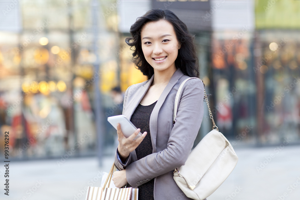 Happy young woman with shopping bag and smart phone