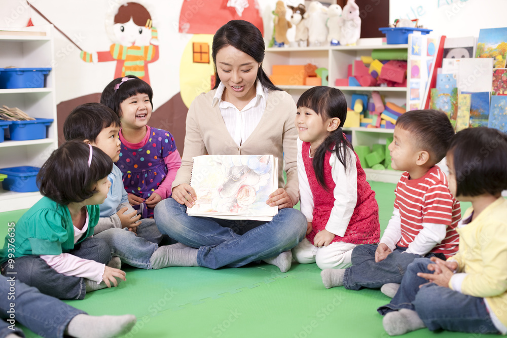 Female teacher showing kindergarten children picture book