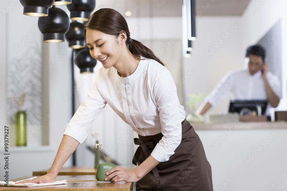 年轻女服务员擦桌子