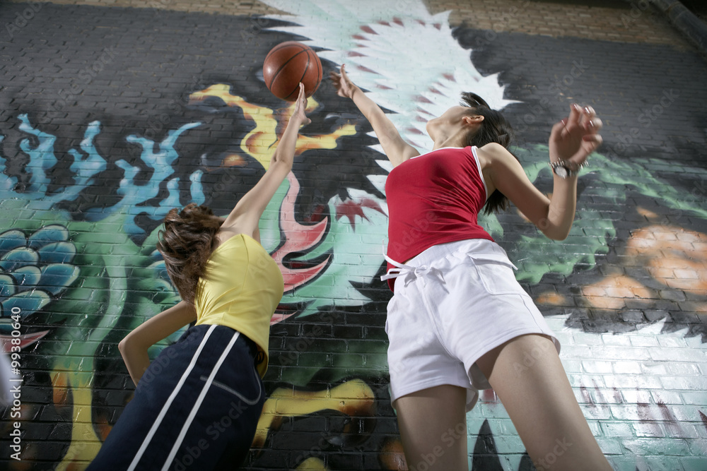 Teenage Girl Jumping For Ball Next To Spay Painted Mural