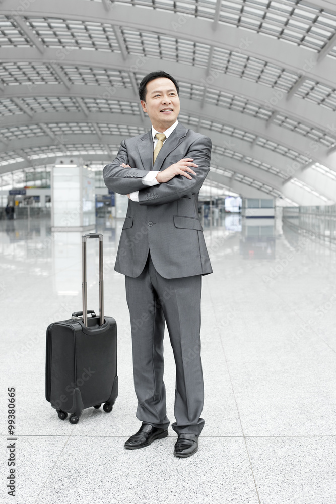 Mature businessman with arms crossed in airport lobby