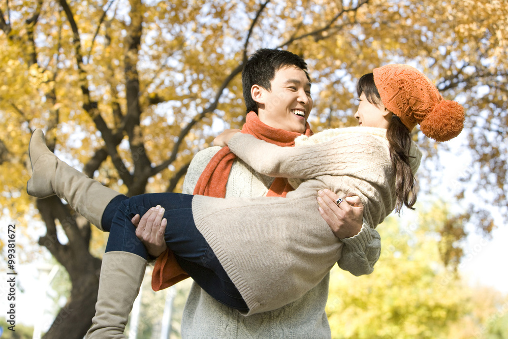 Young Man Carrying a Young Woman in a Park