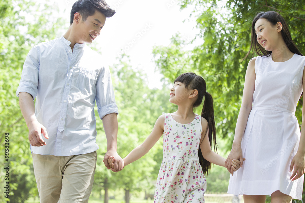 Happy young family walking together in park