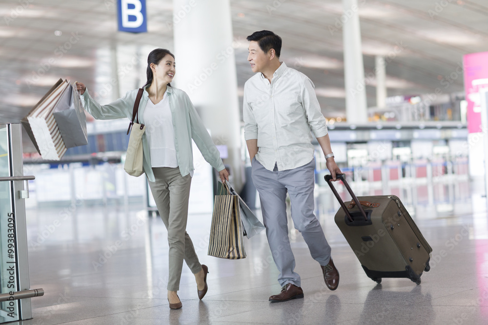 Mature couple walking in airport with shopping bags