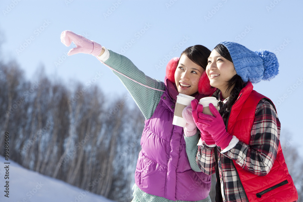 快乐的年轻女人在滑雪场拿着咖啡