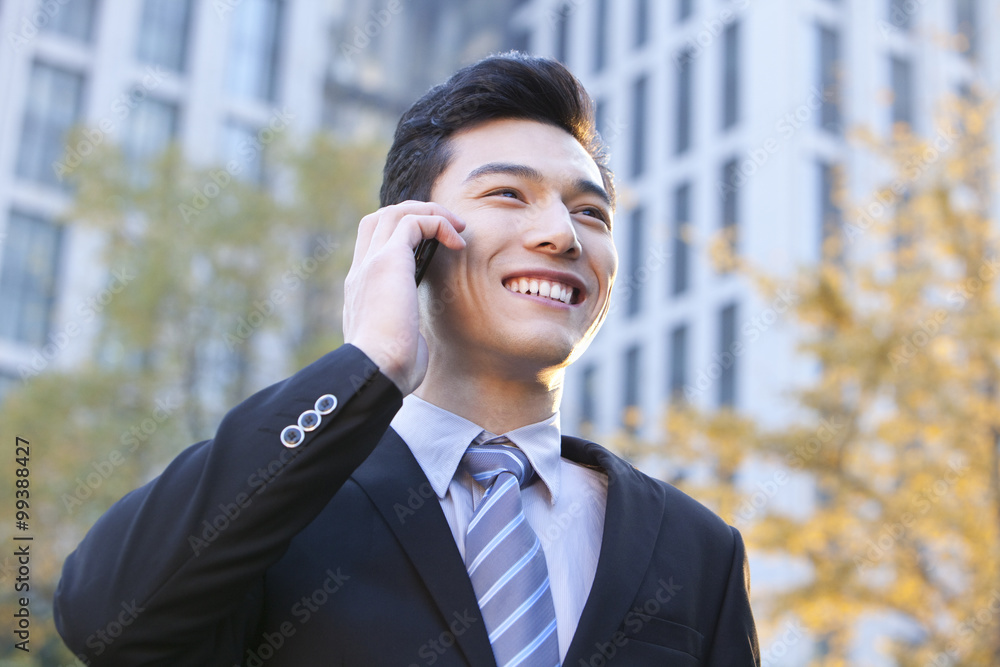 Businessman outside buildings on his mobile phone