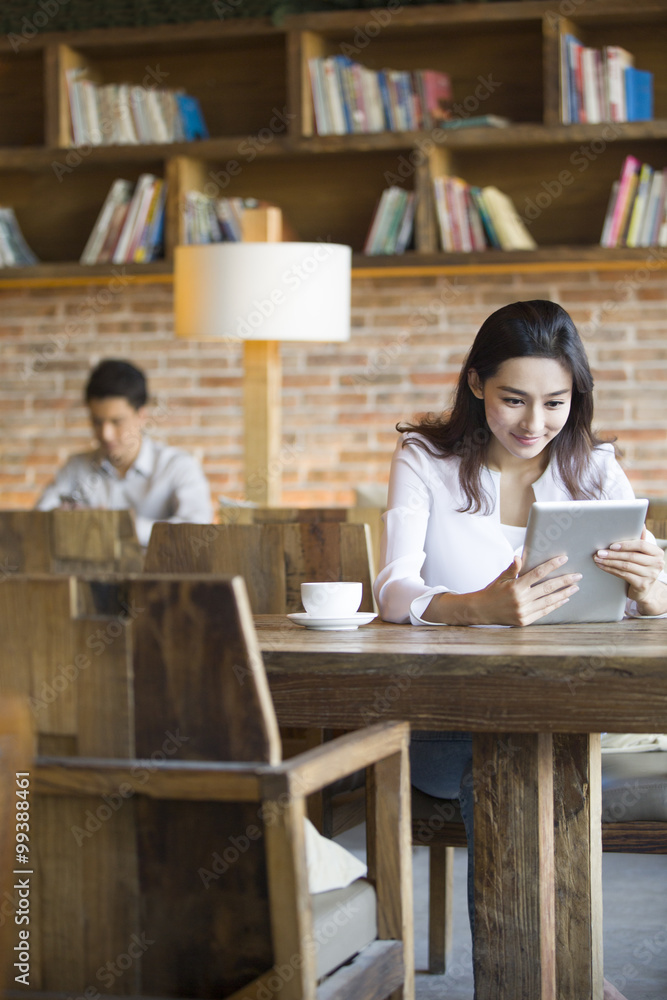 Young woman using digital tablet in cafe