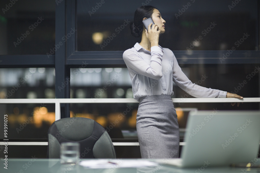 Young businesswoman talking on cell phone in office