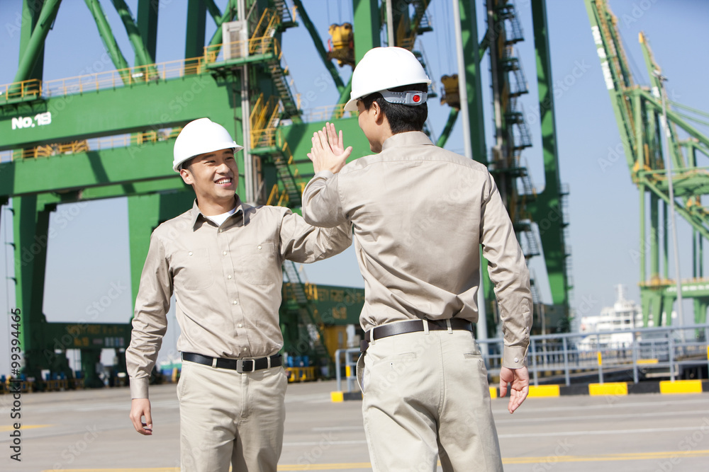 Male shipping industry workers high-fiving