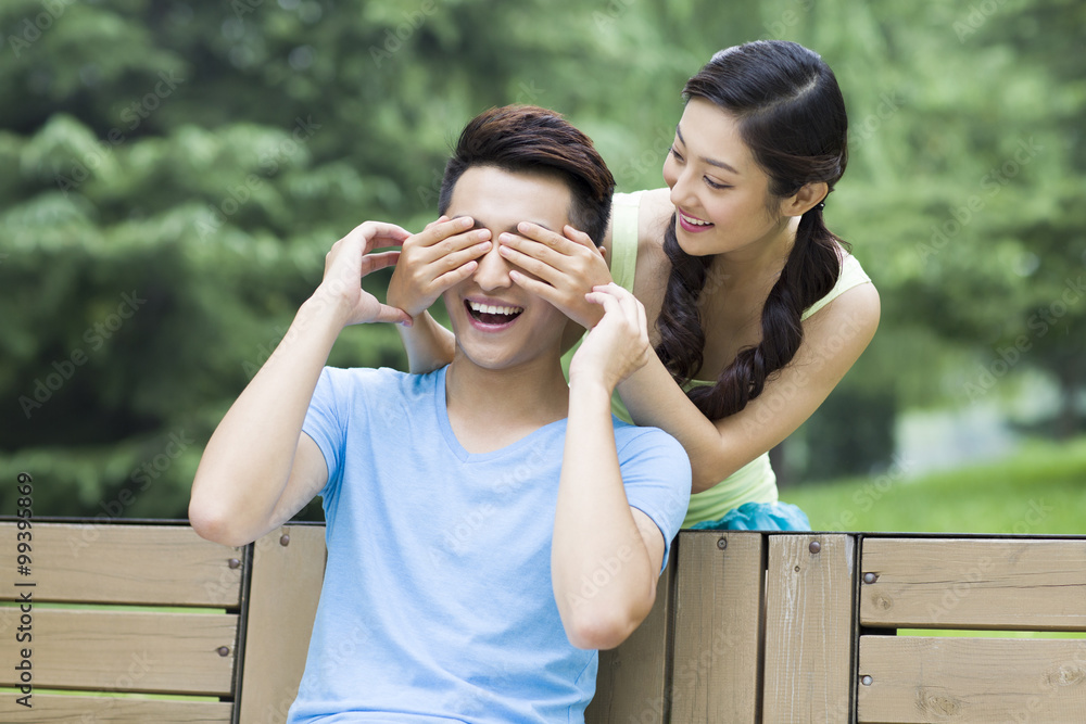 Young woman covering mans eyes