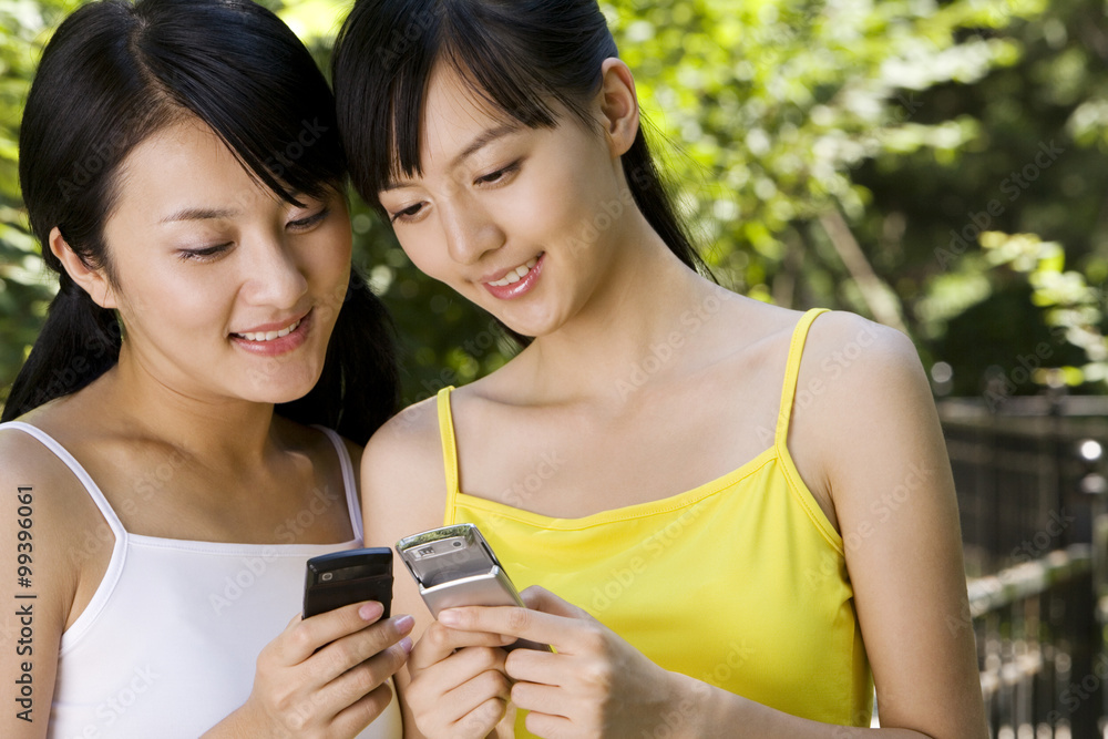 Two friends use their cell phone