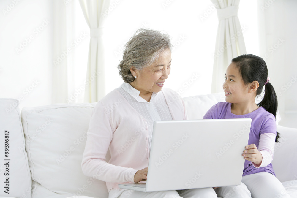 Chinese grandmother with grandaughter using a laptop