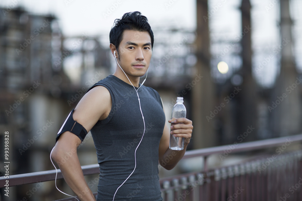 Portrait of young man holding water bottle outdoors†