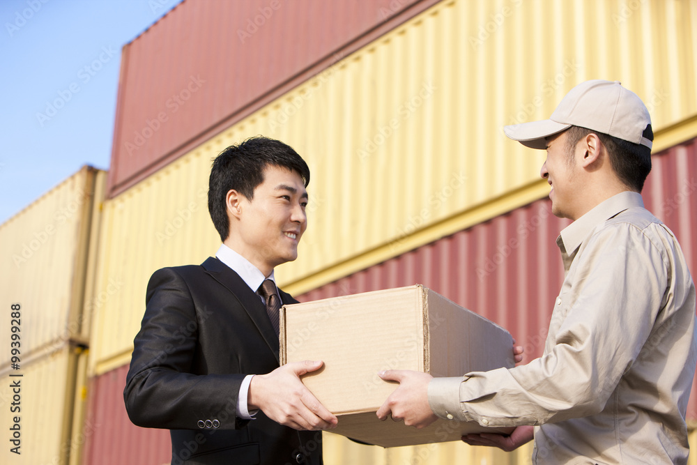 businessman and shipping industry worker giving and receiving a cardboard box