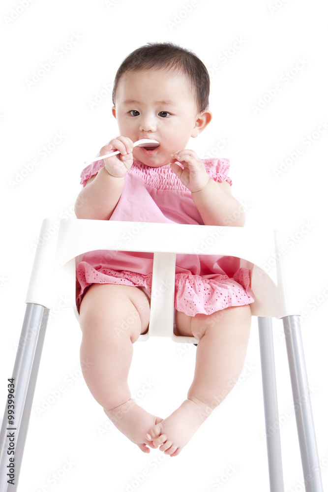 Cute baby girl on baby high chair with a spoon