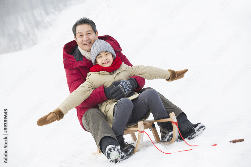 Grandfather and grandson sliding on a sled