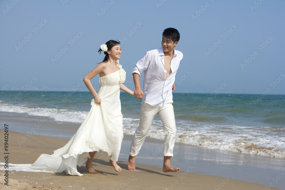 Happy newlyweds running on the beach