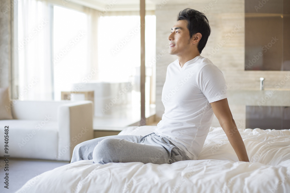 Young man sitting on bed