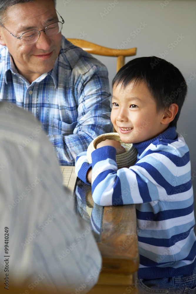 Grandson standing near grandfather at home 