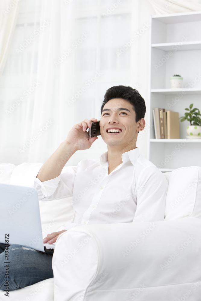 Young man using laptop and phone at home