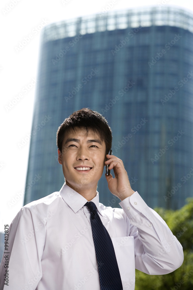 Businessman on phone in front of skyscraper