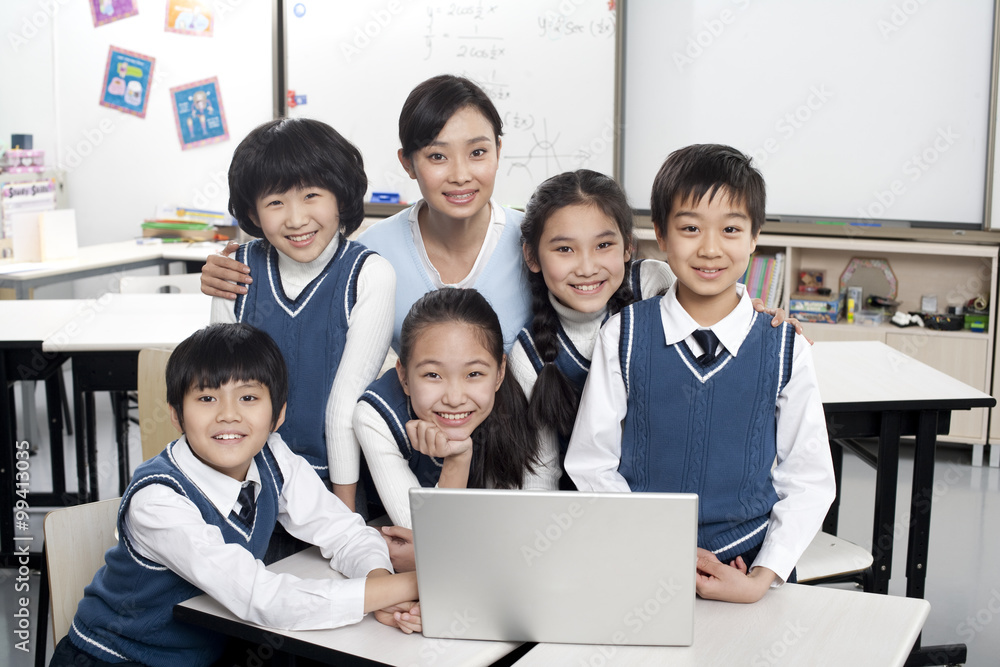 Students and teacher gathered around a computer in the classroom