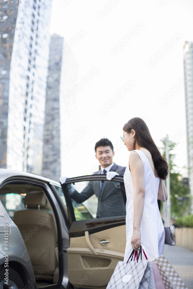 Chauffeur opening car door for a young woman