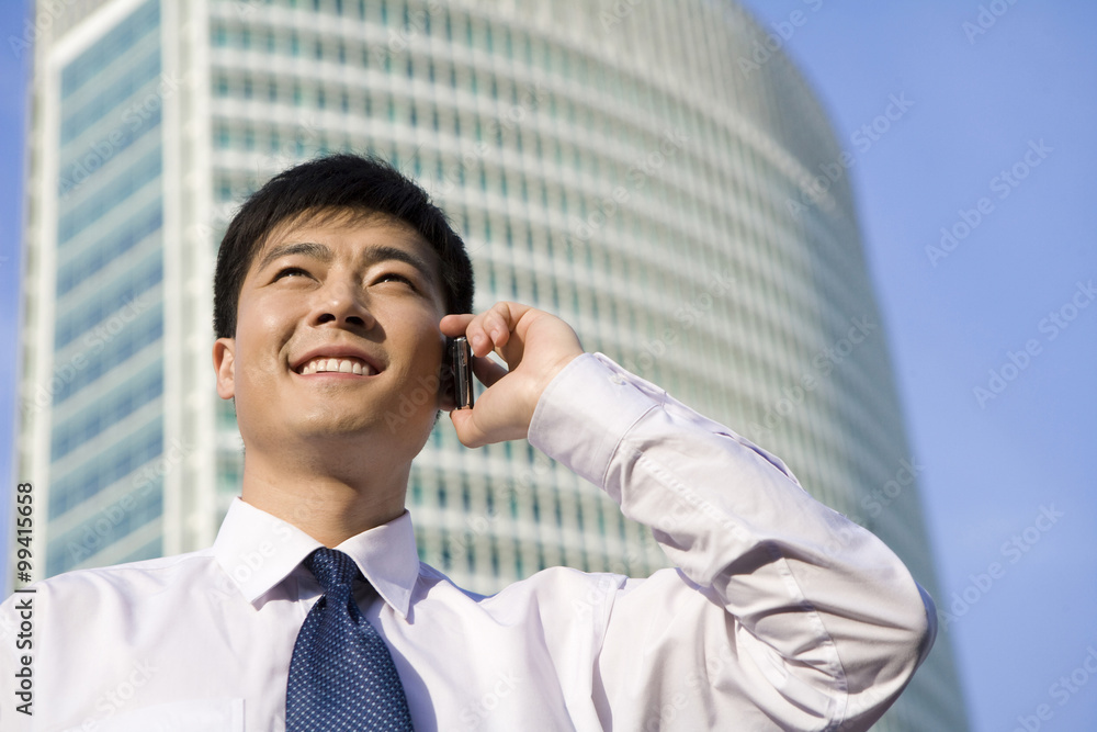 Businessman on phone in front of skyscraper