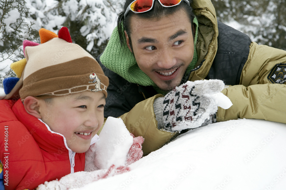 父子制作雪球，躲在雪墙后面