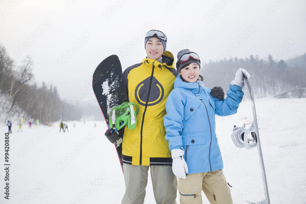 雪地上带滑雪板的年轻情侣