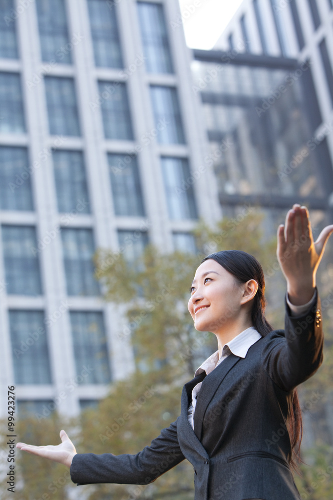 办公楼外张开双臂的女商人