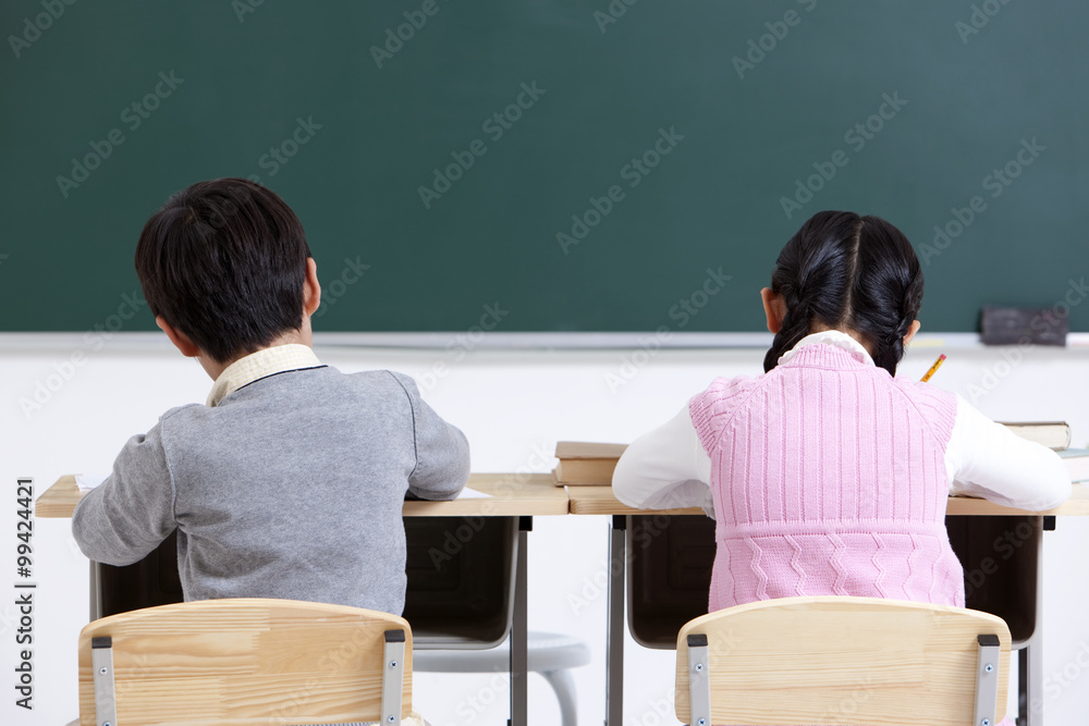 Schoolchildren raising hands in class