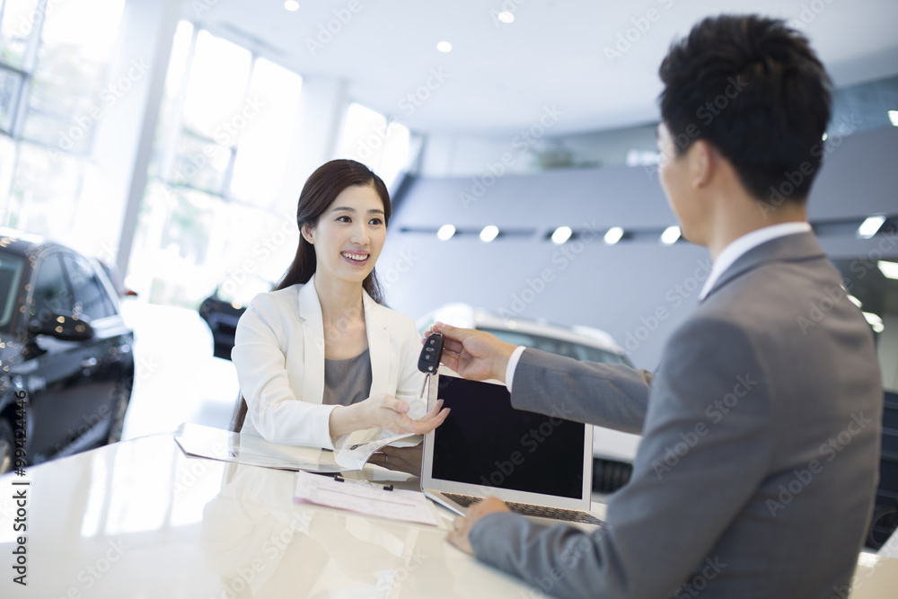 Young businesswoman buying car in showroom