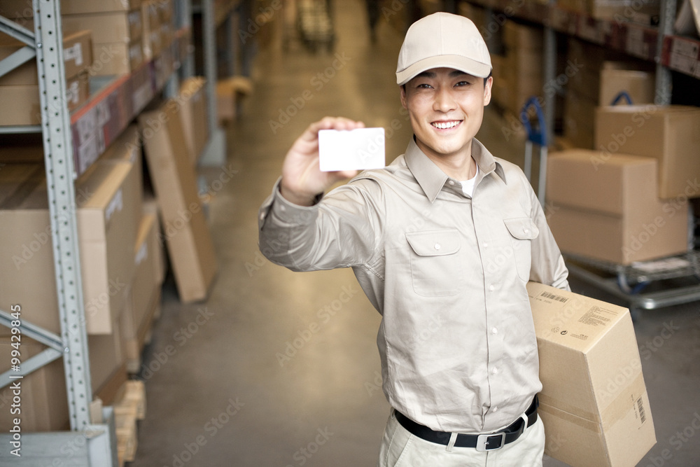 Male Chinese warehouse worker holding up a blank business card