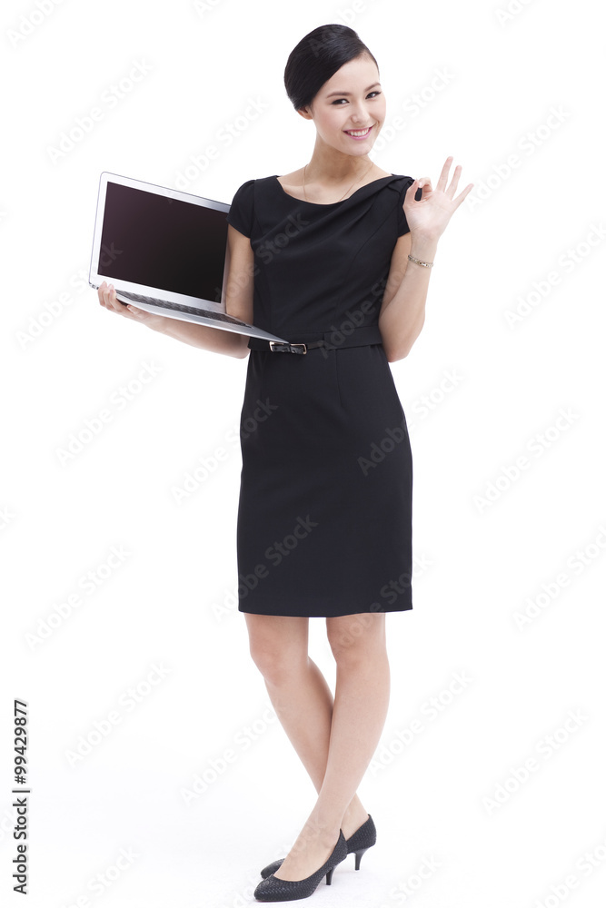 Cheerful businesswoman doing OK sign with laptop in hand