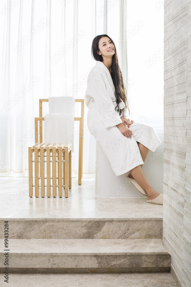 Young woman sitting in bathroom