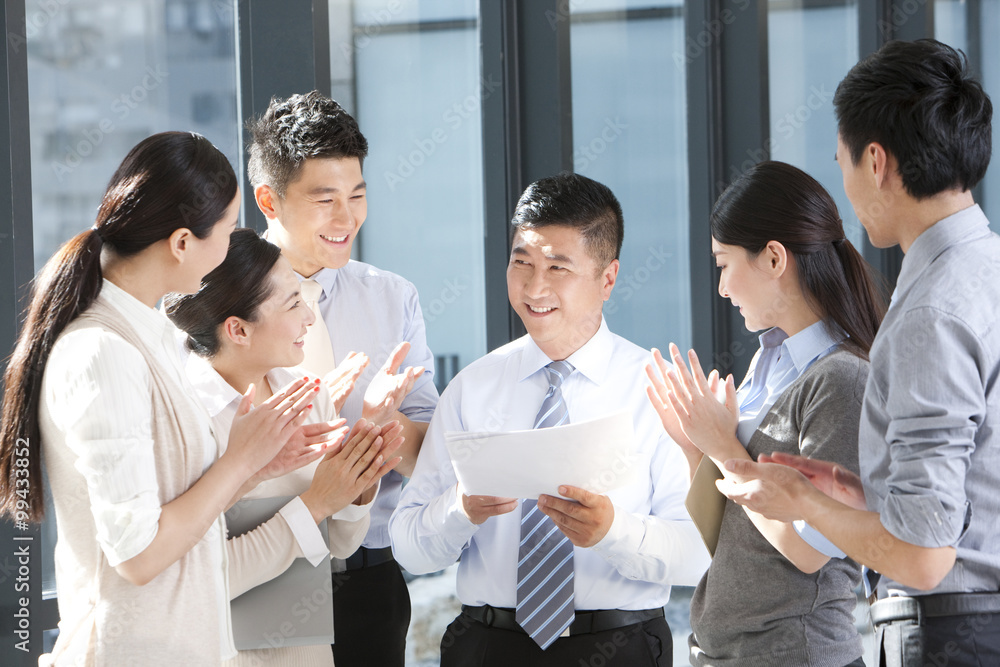 Businesspeople clapping and congratulating team leader